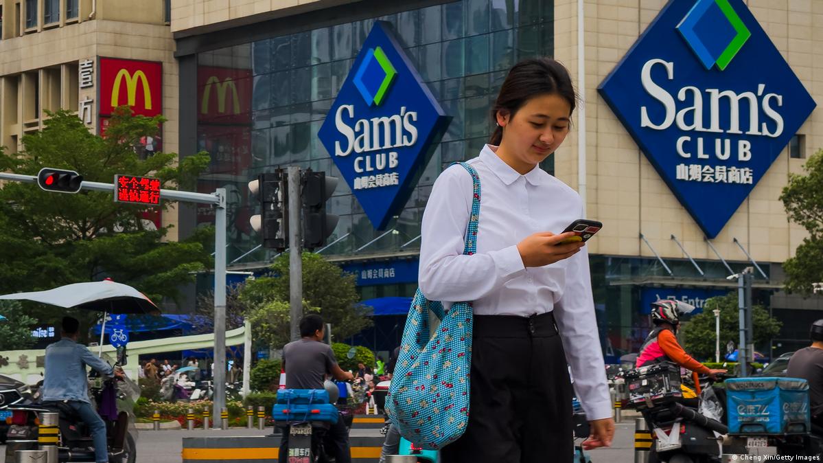深圳街头一名女子拿着手机路过山姆会员店门口
