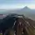 El volcán Krasheninnikov está formado por dos estratovolcanes conectados en una caldera. El lago Kronotskoye y el volcán Kronotsky se ven al fondo. (Archivo)