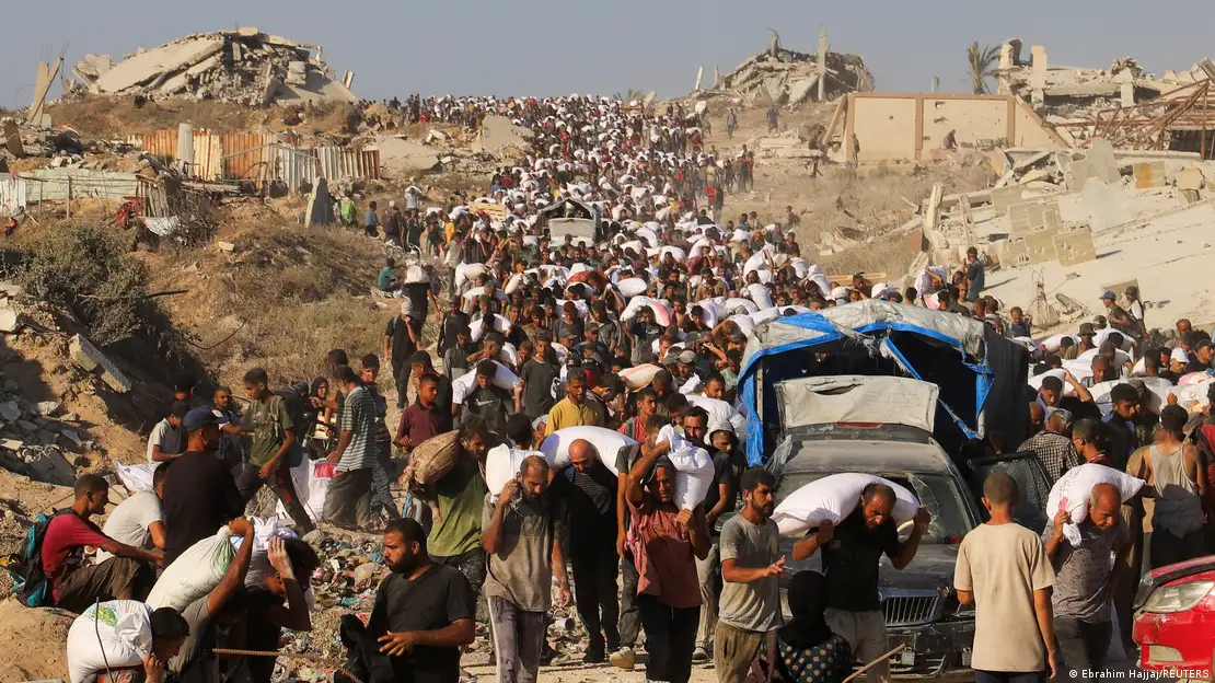 Una multitud de palestinos cargan a pie con alimentos y otros bienes de ayuda humanitaria en Beit Lahia, norte de Franja de Gaza.