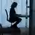 Schwarze Silhouette von einer sitzenden Person am Schreibtisch (Symbolbild)