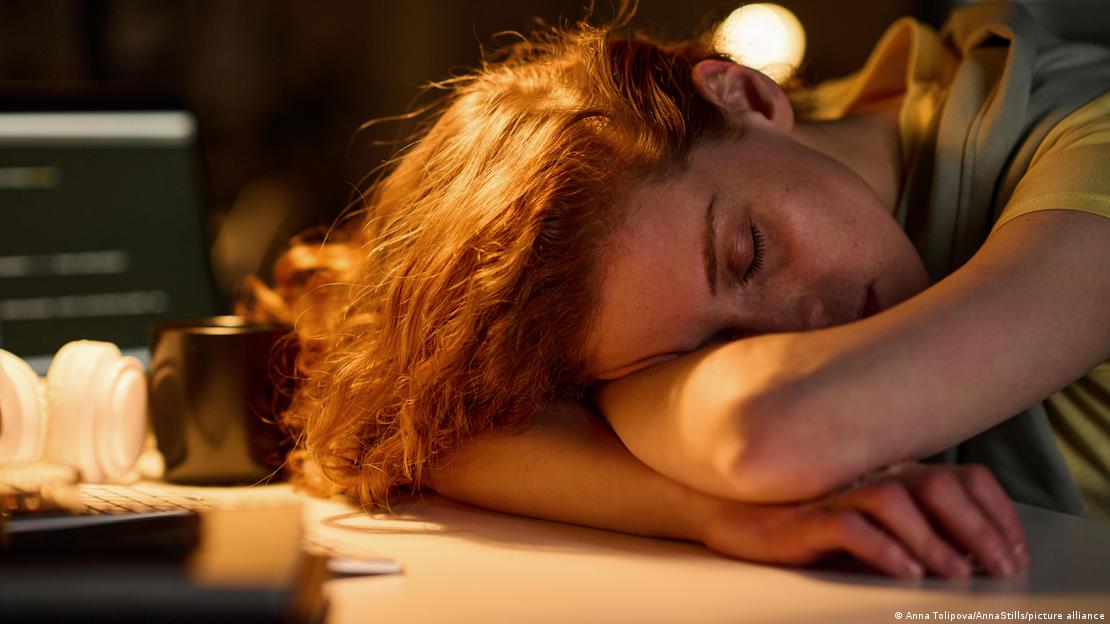 Mujer dormida sobre una mesa de trabajo.