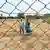Rice farmer Sinnathurai Chitravelayutham and another villager Kirubanantharajah stand next to a fence in Sampur in eastern Sri Lanka's Trincomalee District