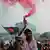 A man holds a flare during a celebration of one year since the uprising that deposed the government of Sheikh Hasina