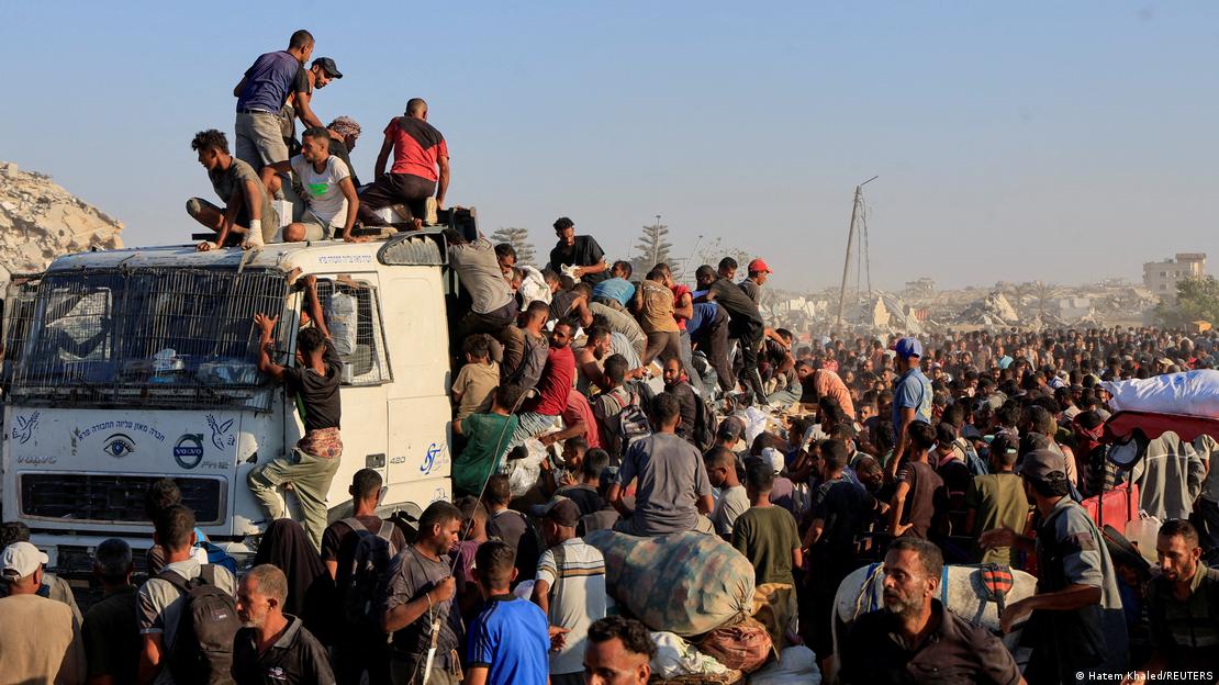 Palestinos subidos a un camión con ayuda humanitaria tratan de conseguir alimentos y productos de primera necesidad en Jan Yunis, Gaza.