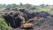 Heavy excavators are seen digging in the aftermath of a landfill collapse, houses are seen in the background Heavy excavators are seen digging in the aftermath of a landfill collapse, houses are seen in the background
