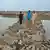 Four people walk along an embankment near the Indus delta, in Pakistan