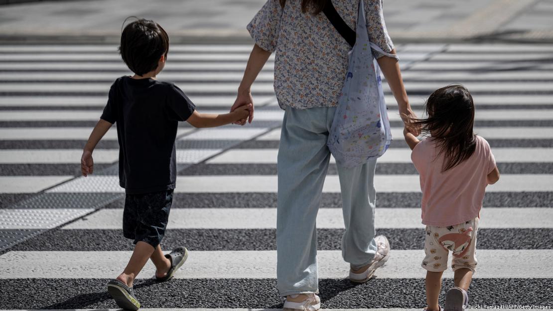 Una madre cruza una avenida en Japón junto a sus dos hijos pequeños.