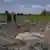 Men look at a landmine that is surrounded by dirt