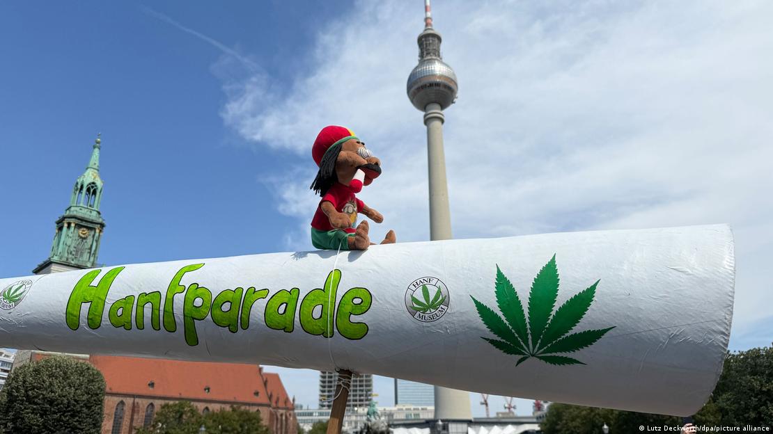 El gran cigarro, con un peluche encima que simula un rastafari fumando marihuana, con la torre de la televisión al fondo.