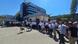 A group of people stand in a semi-circle in the sunshine holding up sheets of white paper with slogans on them. In the background is a blue-and white building. In front of the group are two empty chairs. The blue sky is cloudless. Tirana, Albania, August 11, 2025 A group of people stand in a semi-circle in the sunshine holding up sheets of white paper with slogans on them. In the background is a blue-and white building. In front of the group are two empty chairs. The blue sky is cloudless. Tirana, Albania, August 11, 2025