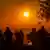 Ein Sonnenuntergang im Taunus, Menschen im Vordergrund sitzen auf einer Bank und beobachten den Himmel