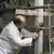 A balding man in a white lab coat (an IAEA inspector) seen working inside an Iranian nuclear facility in 2014