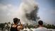 Two men look at a cloud of smoke as it rises above Rafah, one of them is filming the explosion on his cellphone Two men look at a cloud of smoke as it rises above Rafah, one of them is filming the explosion on his cellphone