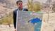 Ministro de Finanzas muestra mapa al aire libre.