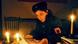 A woman (Nerxhivane Azizi) in a military hat and uniform with a badge marked UCK (Kosovo Liberation Army) on the sleeve reads a newspaper by candlelight A woman (Nerxhivane Azizi) in a military hat and uniform with a badge marked UCK (Kosovo Liberation Army) on the sleeve reads a newspaper by candlelight