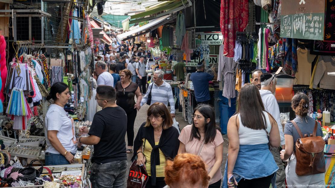 Grupos de personas comprando en un mercado callejero en Tel Aviv.