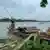 নৌকায় টিন, লাকড়ি নিয়ে বসে আছেন এক ব্যক্তি
