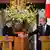 Los ministros alemán y nipón se estrechan las manos desde sendos atriles con las banderas de ambos países detrás durante su rueda de prensa conjunta en Tokio.