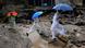 Men holding umbrellas walk on mud and debris caused by floods Men holding umbrellas walk on mud and debris caused by floods