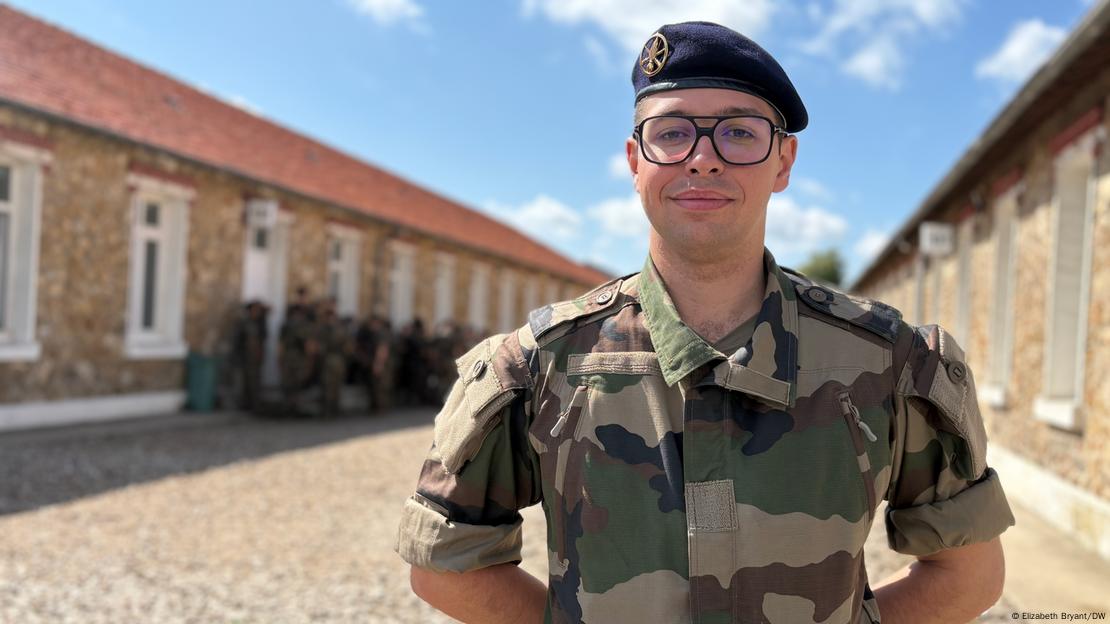 Um jovem de óculos e fardado posando para foto