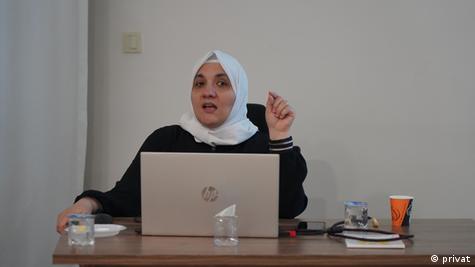 İstanbul merkezli Suriye Diyalog Merkezi'nden Kinda Hawasli, bir büroda masada oturuyor, önünde diz üstü bilgisayarı duruyor