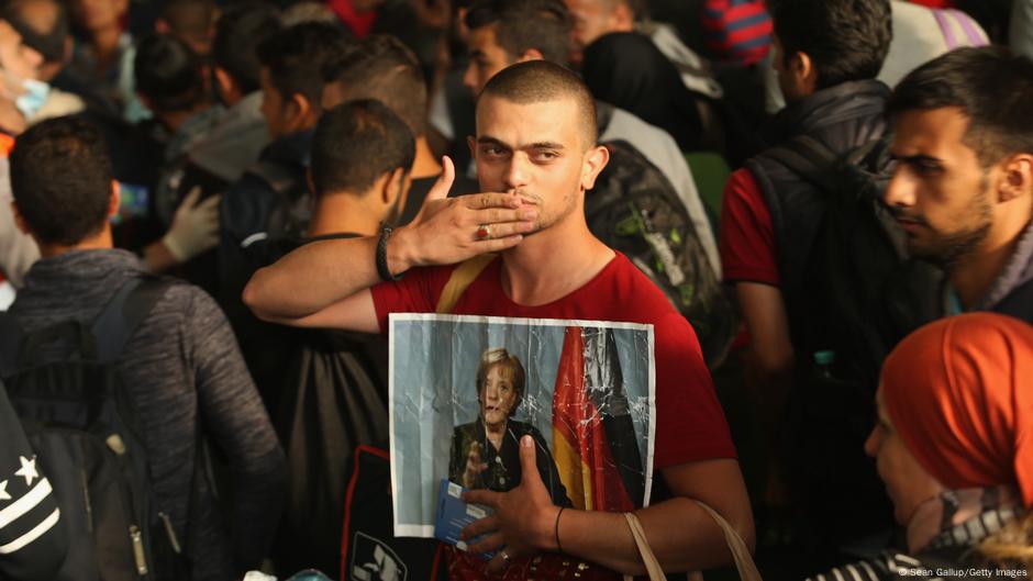 Migrant iz Sirije sa fotografijom Angele Merkel, pre 10 godina (5.09.2015) na železničkoj stanici u Minhenu. Stigao je tada zajedno sa hiljadama drugih migranta, koje je Mađarska izbacila iz zemlje na austrijkoj granici.