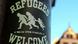 A sticker with refugees welcome, bring your families written in white on a back background stuck to a post in Freiburg Germany in December 2016 A sticker with refugees welcome, bring your families written in white on a back background stuck to a post in Freiburg Germany in December 2016