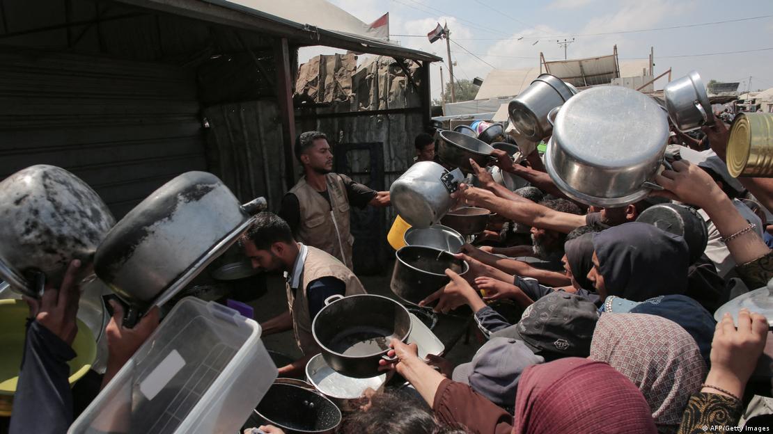 Palestinos sostienen sus ollas vacías para pedir alimentos a una cocina benéfica en Jan Yunis, en el sur de la Franja de Gaza (21.08.2025)