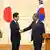 Lee Jae Myung and Shigeru Ishiba shake hands for the press in front of South Korean and Japanese flags