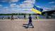 A man with a Ukrainian flag walks along a canal in Germany. A man with a Ukrainian flag walks along a canal in Germany.