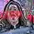 A man looking at a smartphone walks past a mural featuring the face of convicted murderer Erin Patterson