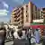 Personas congregadas ante un edificio con destrozos.