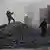 Three people, one a woman with a shovel, seen in a cloud of dust as coal is unloaded from a truck n China