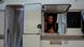 A man poses for a picture through the window of the small caravan where he lives in Ibiza A man poses for a picture through the window of the small caravan where he lives in Ibiza