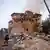Rescatistas frente a un edificion destruido, rodeado de escombros.