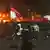 Protesters carrying Indonesian flags walk by as the local parliament building is engulfed in flames on Aug 29, 2025.