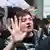 A person with reddish hair and a bloody nose holds up a bloodied hand while speaking to a police officer in Berlin