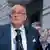 Former New York City Mayor Rudy Giuliani, in a blue blazer and patriotic tie, gestures with his hands as he speaks 