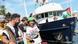 Varias personas sonrientes caminan por un puerto, detrás, a un costado, un barco con canderas palestinas. Varias personas sonrientes caminan por un puerto, detrás, a un costado, un barco con canderas palestinas.