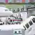 Blick auf eine Gangway an einem Flugzeug, auf dem "Airlines" zu lesen ist: Man erkennt, dass eine Gruppe von Menschen durch die Gangway in den Flughafen laufen