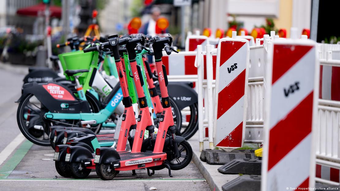 Bicicletas y patinetes eléctricos junto a una valla.