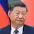Xi Jinping wears an earpiece while sitting in front of Chinese and Mongolian flags during a trilateral meeting that included Russian President Vladimir Putin