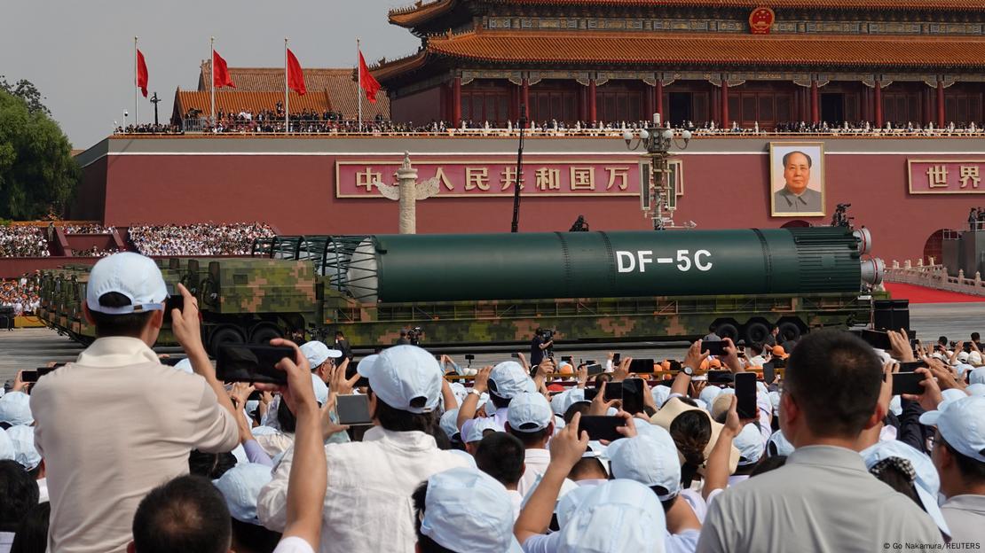 Pessoas observam mísseis em desfile que celebrou fim da Segunda Guerra Mundial. Ao fundo, edifício em estilo chines da Praça da Paz Celestial Pessoas observam mísseis em desfile que celebrou fim da Segunda Guerra Mundial. Ao fundo, edifício em estilo chines da Praça da Paz Celestial