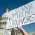 A hand holding a sign that reads "I stand with the survivors" is seen in front of the US Capitol