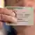 A person holds up an incomplete German ID card, with all the pertinent data except for the nationality left blank and their fingers obscuring the photo on the card. Symbolic photo taken in March 2025.