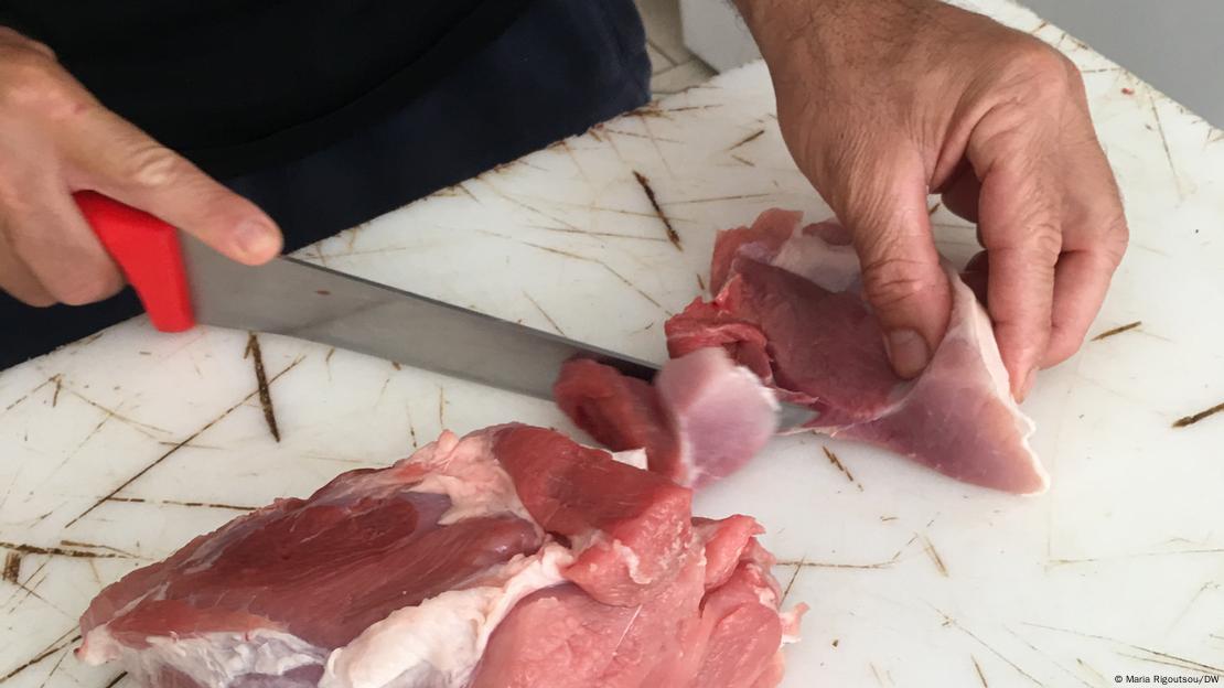 Κρεοπώλης τεμαχίζει ένα κομμάτι κρέας