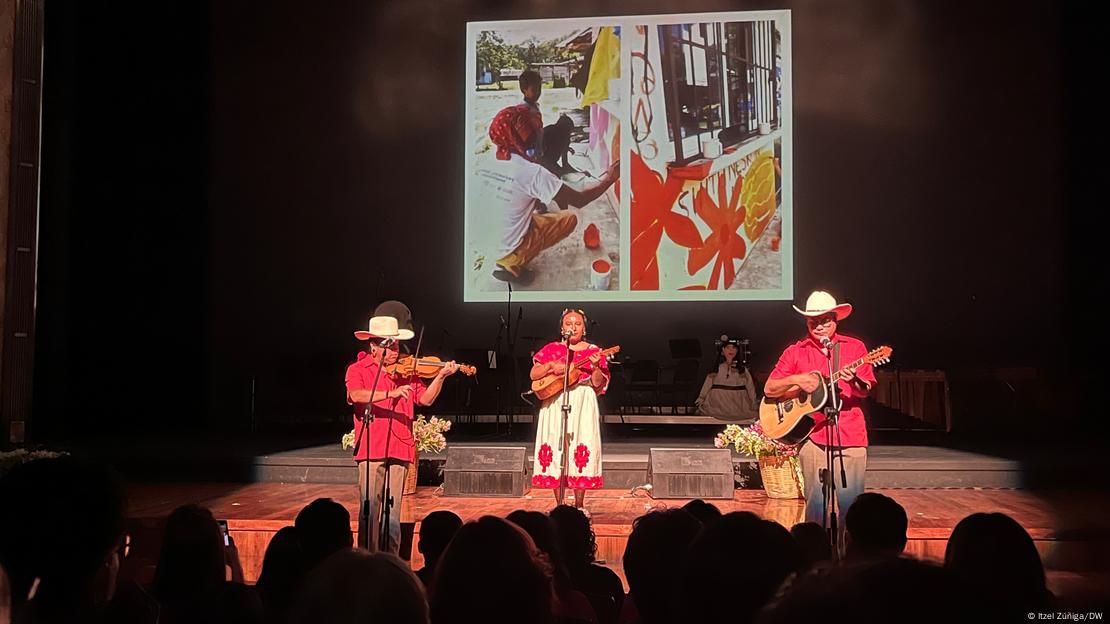 Tres artistas interpretan instrumentos sobre un escenario.