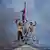 Three protesters stand on top of Nepal's parliament building, which was attacked by protesters