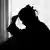 Silhouette einer Frau vor einem Fenster, die sich nachdenklich an die Stirn fasst