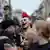 Ein Demonstrant mit einem roten Irokesenhaarschnitt steht inmitten einer Gruppe und hebt die Faust